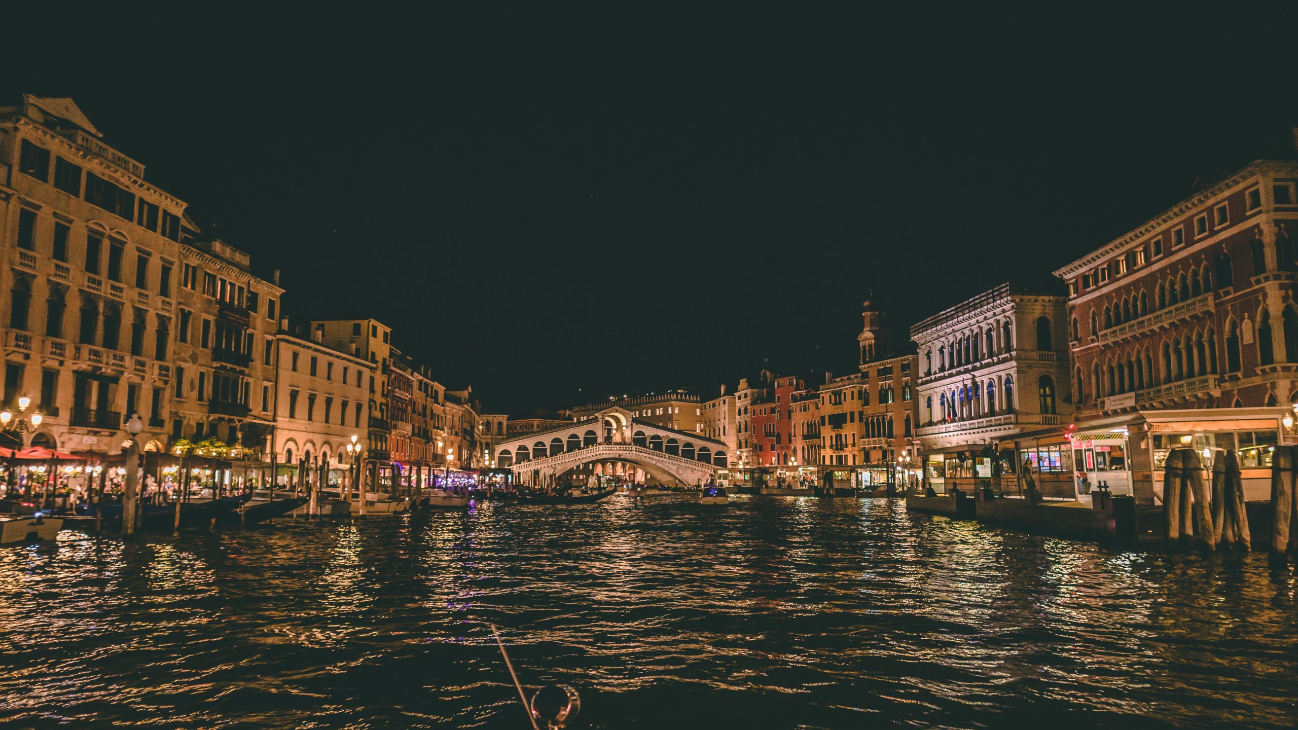 Explore the enchanting night scene of Venice's famous Rialto Bridge reflecting on canal waters.